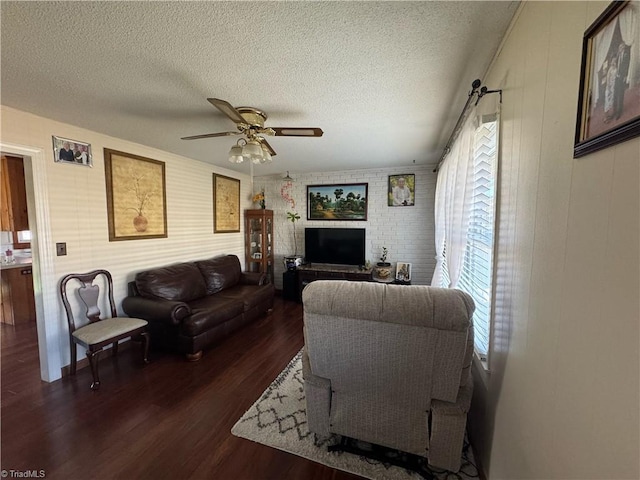 living room featuring a textured ceiling, ceiling fan, and dark wood finished floors