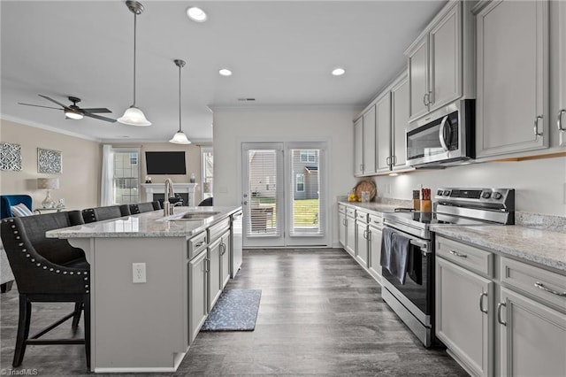 kitchen featuring an island with sink, stainless steel appliances, a kitchen bar, ceiling fan, and sink