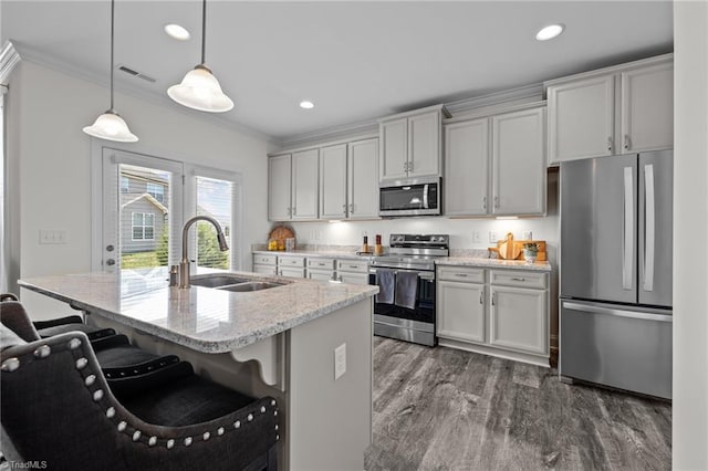 kitchen with light stone counters, a breakfast bar area, sink, stainless steel appliances, and decorative light fixtures