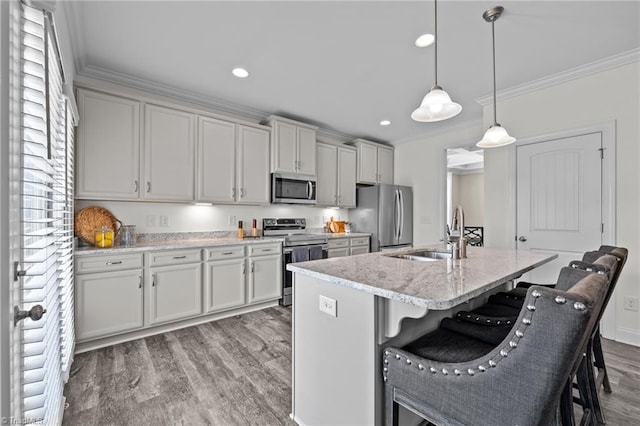 kitchen with light stone counters, hanging light fixtures, sink, stainless steel appliances, and a breakfast bar area