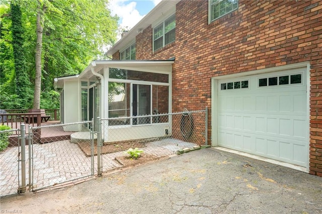 1315 Waybridge Ln, Winston-Salem, NC 27103 - view of side of property with a garage, a sunroom, brick siding, asphalt driveway, and a gate