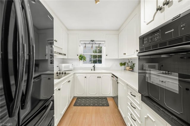 1315 Waybridge Ln, Winston-Salem, NC 27103 - kitchen featuring black appliances, light wood-type flooring, white cabinetry, and backsplash