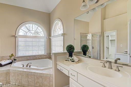 bathroom with vanity, vaulted ceiling, and independent shower and bath