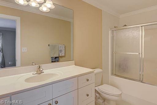 full bathroom featuring toilet, ornamental molding, combined bath / shower with glass door, and vanity