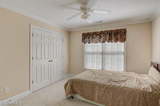 carpeted bedroom with crown molding, ceiling fan, and a closet