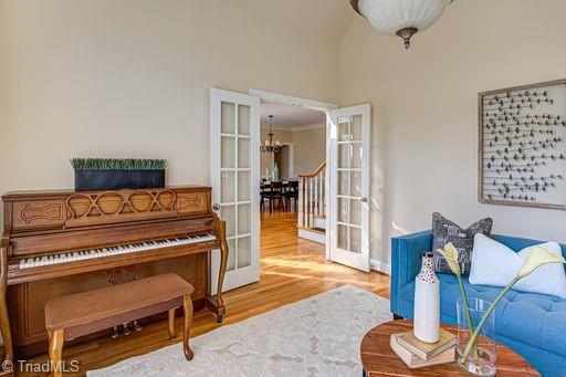 interior space with light wood-type flooring, french doors, ornamental molding, and a notable chandelier