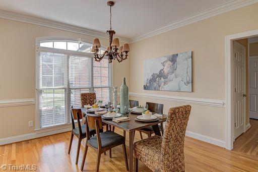 dining space with a chandelier, crown molding, and light hardwood / wood-style flooring