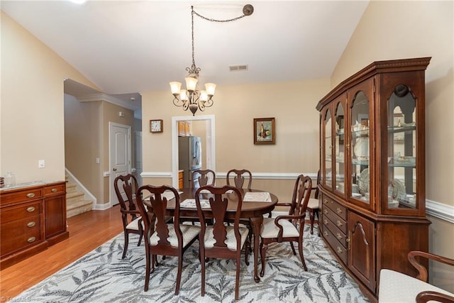 dining space featuring a notable chandelier, lofted ceiling, and light hardwood / wood-style flooring