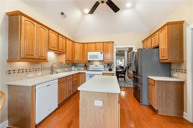 kitchen with light wood-type flooring, white appliances, vaulted ceiling, and sink