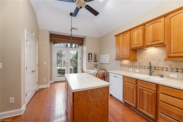 kitchen with light wood-type flooring, white dishwasher, vaulted ceiling, a center island, and hanging light fixtures