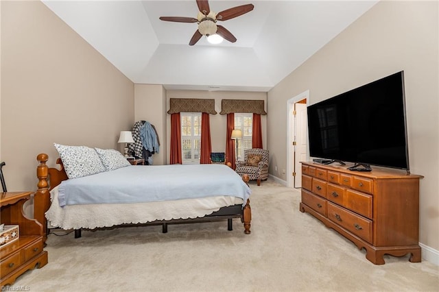 bedroom with lofted ceiling, light colored carpet, ceiling fan, and a tray ceiling