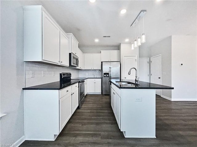 kitchen featuring stainless steel appliances, sink, white cabinets, dark hardwood / wood-style floors, and an island with sink