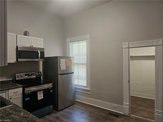 kitchen featuring dark stone counters, dark wood-type flooring, sink, white cabinets, and appliances with stainless steel finishes