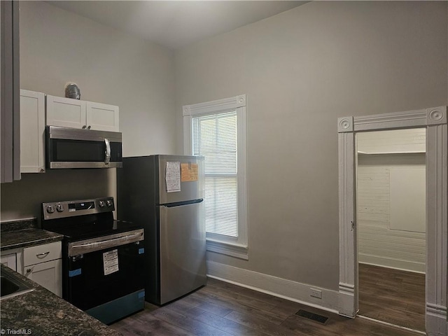 kitchen featuring appliances with stainless steel finishes, white cabinetry, baseboards, visible vents, and dark wood-style floors