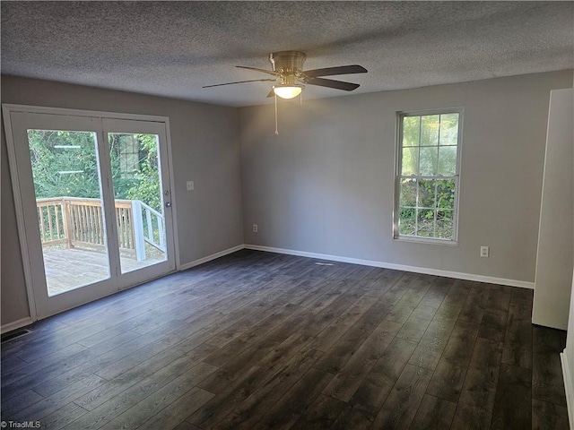empty room featuring a textured ceiling, dark wood-style floors, plenty of natural light, and ceiling fan