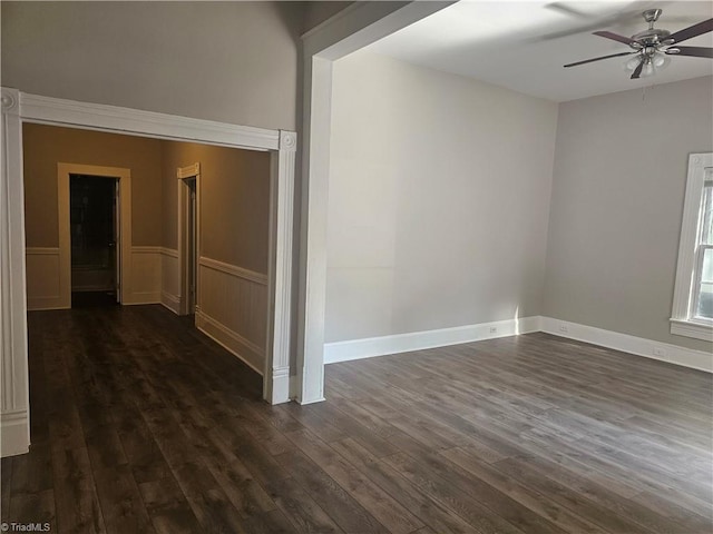 spare room with ceiling fan, dark wood-style floors, and a wainscoted wall