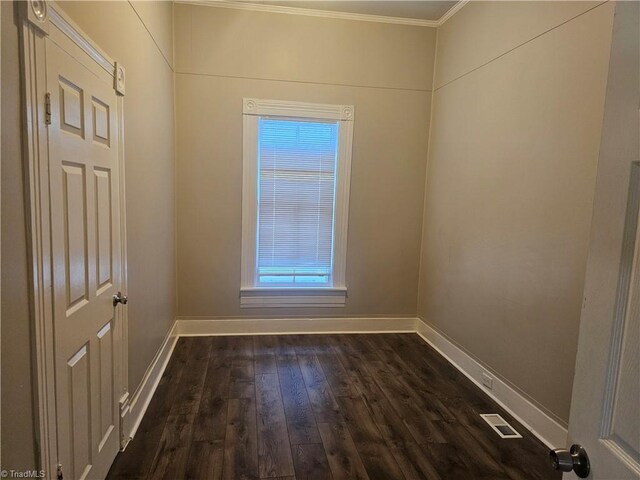empty room with visible vents, ornamental molding, dark wood finished floors, and baseboards