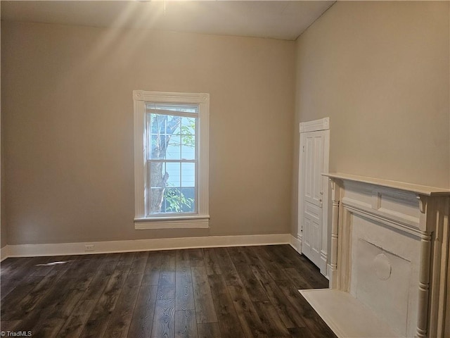 unfurnished living room featuring baseboards and dark wood-style floors