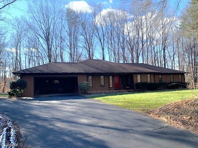 ranch-style home featuring driveway, a garage, and a front lawn