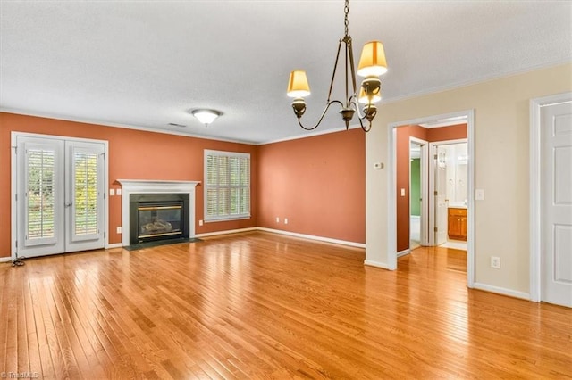 unfurnished living room featuring hardwood / wood-style floors, a notable chandelier, and crown molding