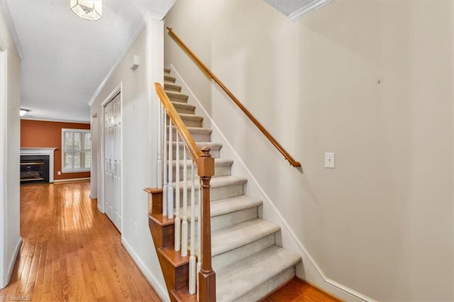 stairs featuring crown molding and hardwood / wood-style floors