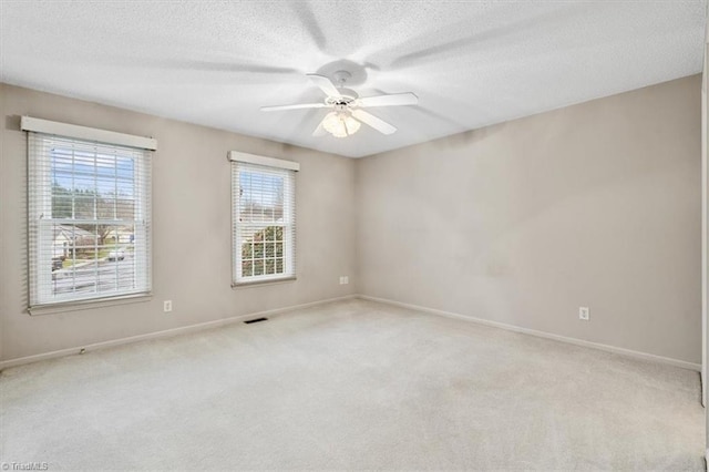 carpeted spare room featuring ceiling fan and a textured ceiling