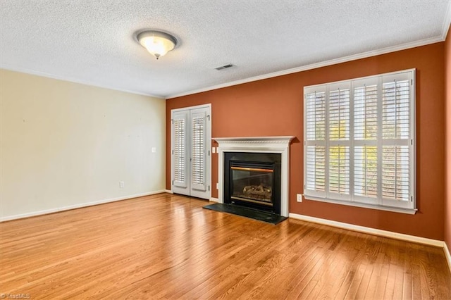 unfurnished living room with a textured ceiling, light wood-type flooring, and crown molding