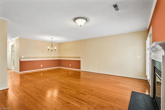 unfurnished living room with a chandelier, a textured ceiling, and hardwood / wood-style flooring