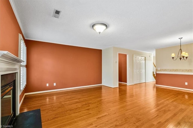 unfurnished living room with hardwood / wood-style floors, a textured ceiling, and a notable chandelier