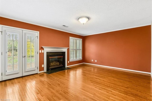 unfurnished living room with wood-type flooring, a textured ceiling, and ornamental molding