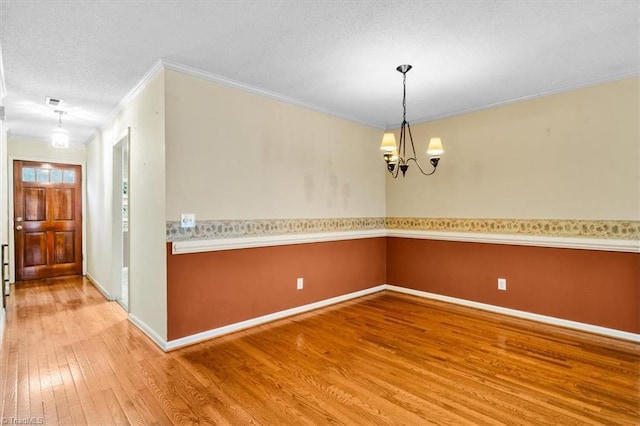 interior space featuring a textured ceiling, wood-type flooring, crown molding, and an inviting chandelier