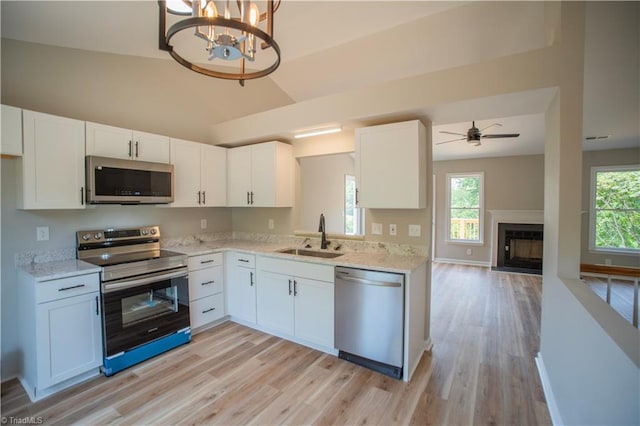 9048 Jefferson Woods Dr, King, NC 27045 - kitchen featuring appliances with stainless steel finishes, light wood-style flooring, white cabinets, and lofted ceiling