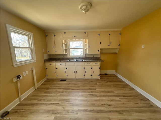 kitchen featuring dark countertops, baseboards, and a sink