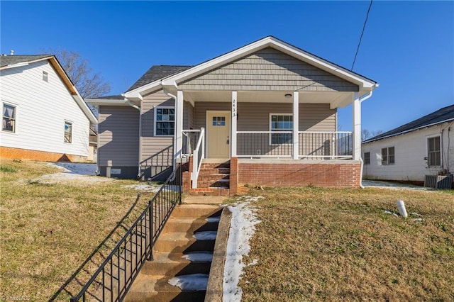 bungalow-style house with a porch, cooling unit, and a front lawn