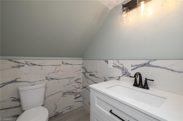 bathroom with vanity, vaulted ceiling, tile walls, and toilet