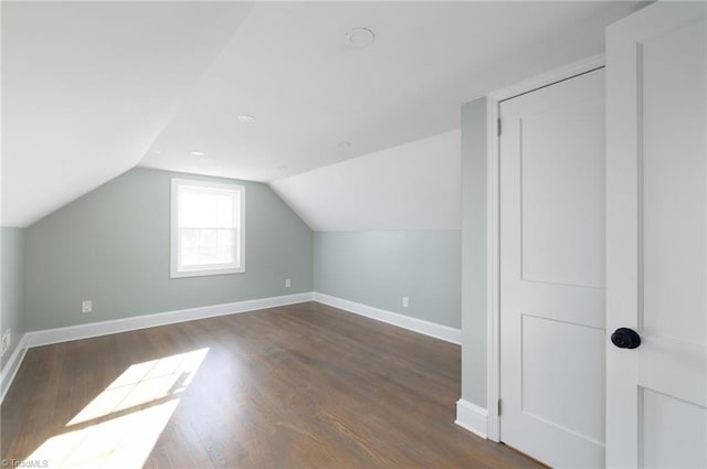 additional living space featuring dark wood-type flooring and vaulted ceiling