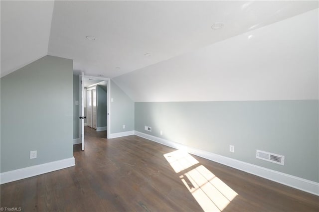 additional living space with dark wood-type flooring and vaulted ceiling