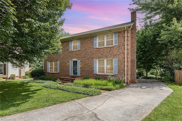 1601 Heraldry Ln, Greensboro, NC 27455 - colonial house with a chimney, concrete driveway, a lawn, and brick siding