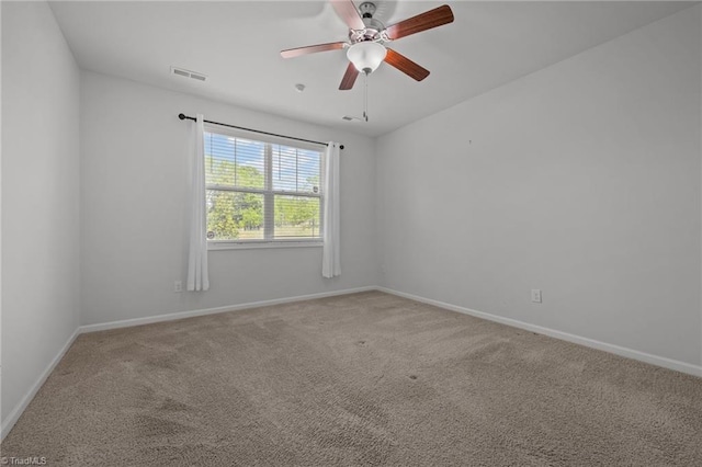 carpeted empty room with baseboards, a ceiling fan, and visible vents