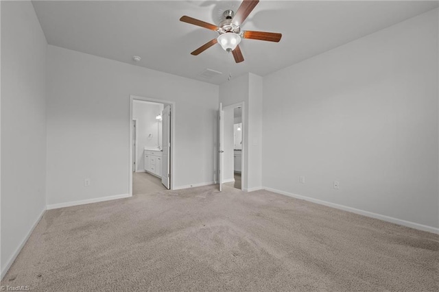 unfurnished bedroom featuring light carpet, ensuite bathroom, baseboards, and ceiling fan