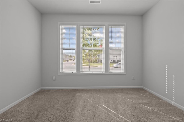 carpeted spare room featuring baseboards and visible vents