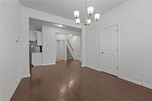 unfurnished dining area featuring baseboards, an inviting chandelier, stairway, and dark wood finished floors