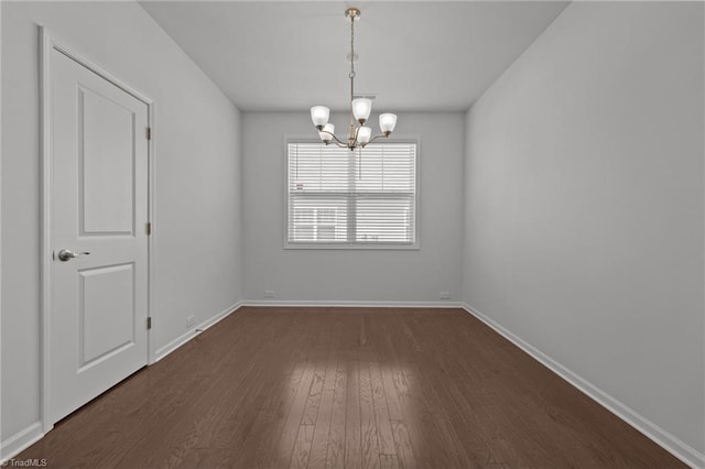 unfurnished dining area with baseboards, dark wood-style flooring, and an inviting chandelier