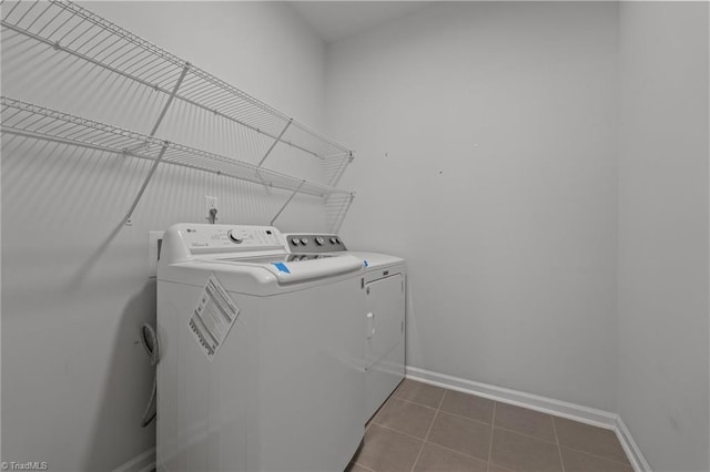 laundry area featuring dark tile patterned floors, baseboards, washer and dryer, and laundry area