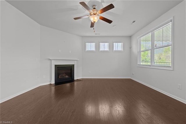 unfurnished living room featuring a fireplace with flush hearth, dark wood finished floors, visible vents, baseboards, and ceiling fan