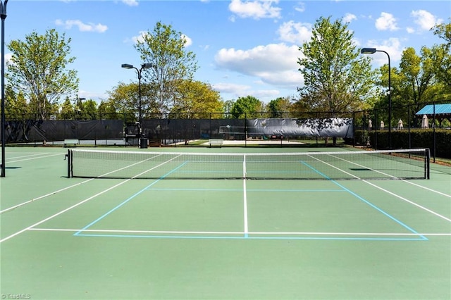 view of tennis court with community basketball court and fence