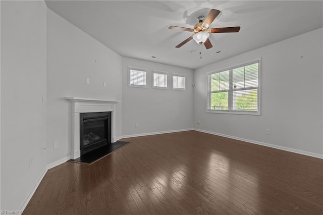 unfurnished living room featuring visible vents, a ceiling fan, dark wood-type flooring, baseboards, and a glass covered fireplace