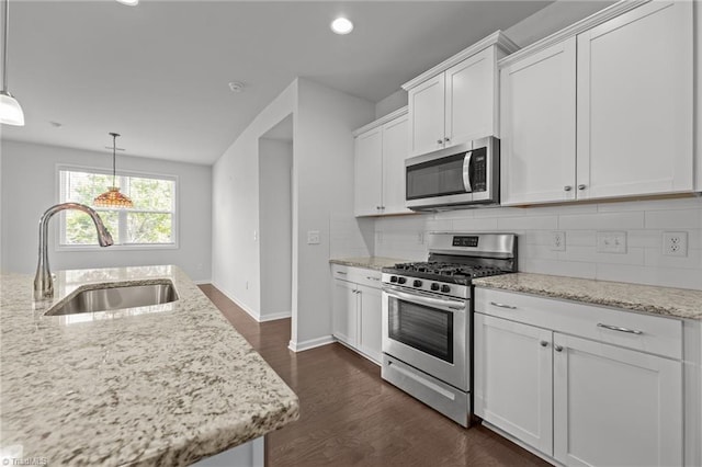 kitchen featuring white cabinets, stainless steel appliances, a sink, dark wood-type flooring, and tasteful backsplash