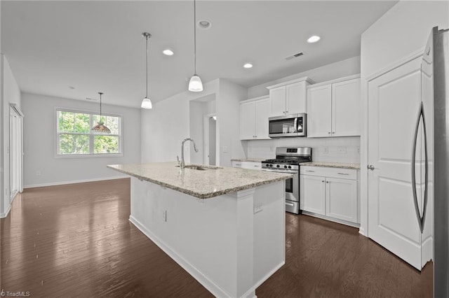 kitchen with dark wood finished floors, appliances with stainless steel finishes, white cabinetry, and a sink