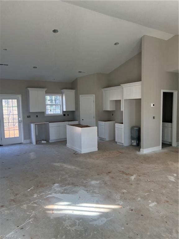 kitchen with white cabinetry, a kitchen island, and lofted ceiling